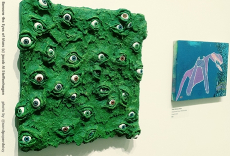 An emerald green knobby square piece of art protruding all over with bulging human eyes of all colors, in 3D. By artist Jacob M Steffenhagen.