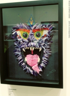 A mixed media depiction of a fanged and furry beast, at once whimsical and scary, somewhat resembling a monkey or baboon. By artist Brittany Scheller.
